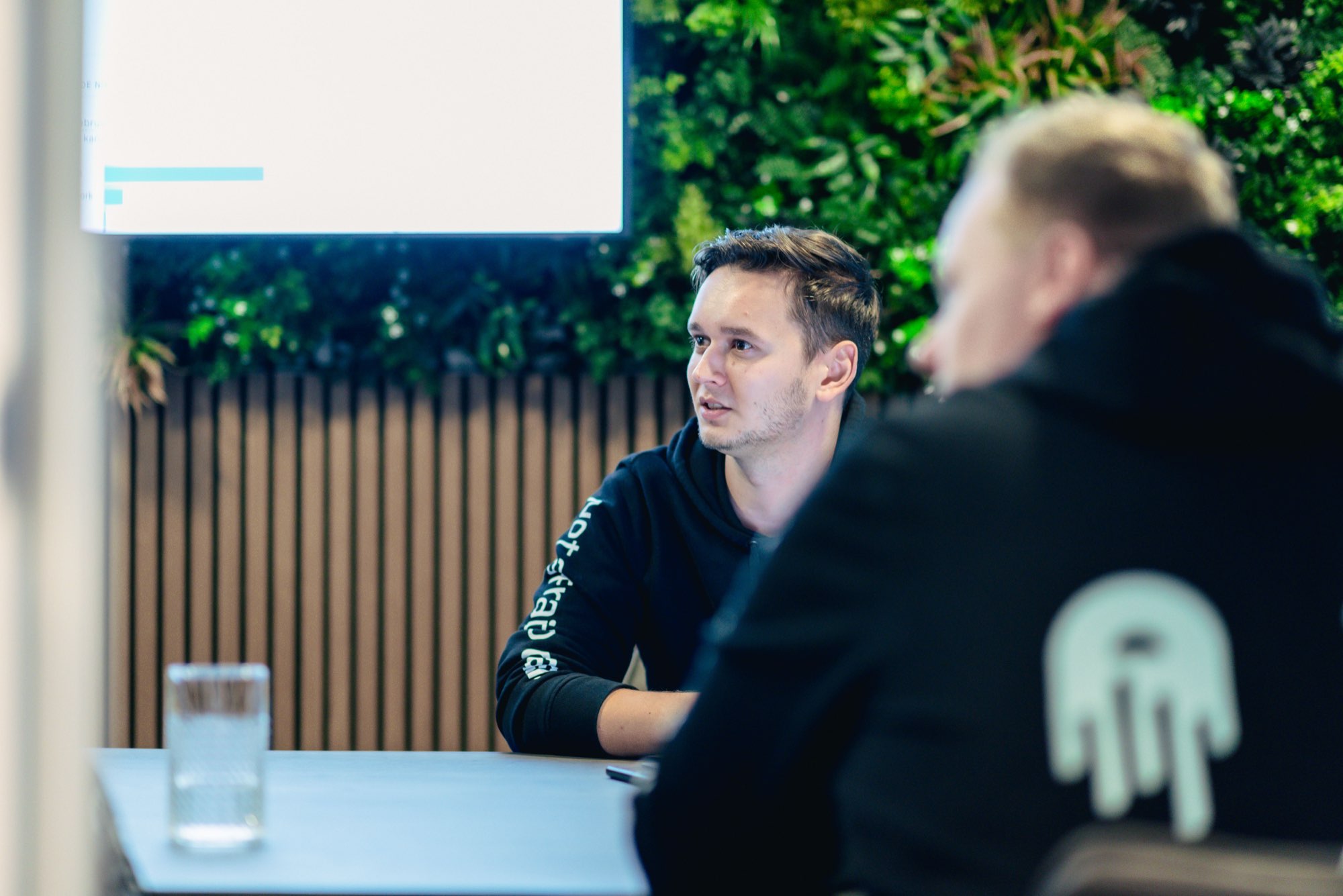 Medewerker in gesprek aan tafel voor de plantenwand