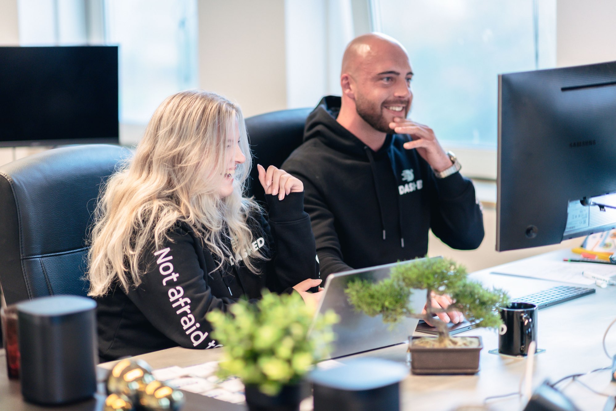 Collega's kijken samen naar een laptop op de werkplek
