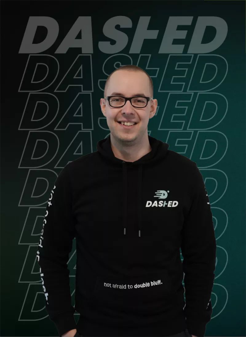Een persoon met een bril draagt een zwarte DAS-IED hoodie met de tekst "not afraid to double bluff," voor een achtergrond met herhaaldelijke "DAS-IED" tekst in groen.