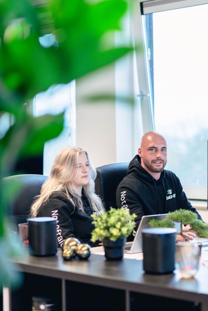 Twee collega's overleggen aan een bureau met planten op de voorgrond
