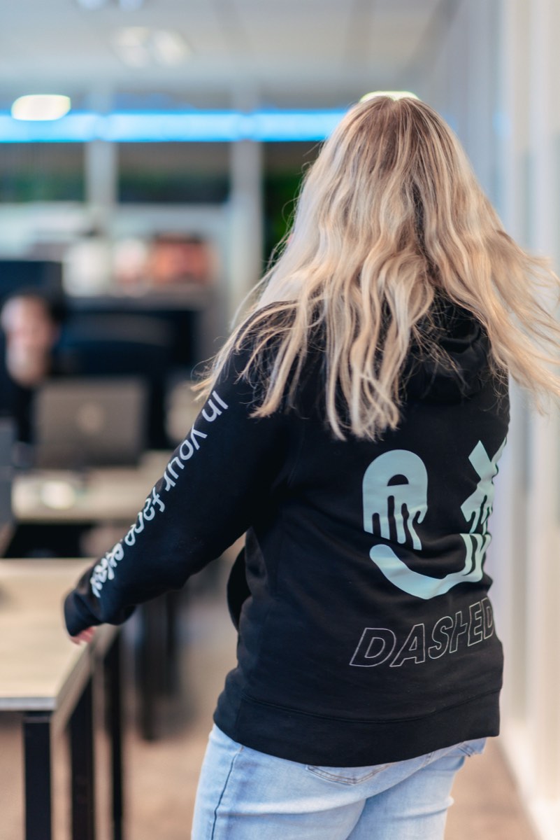 Medewerker met Dashed-hoodie loopt door de kantoortuin