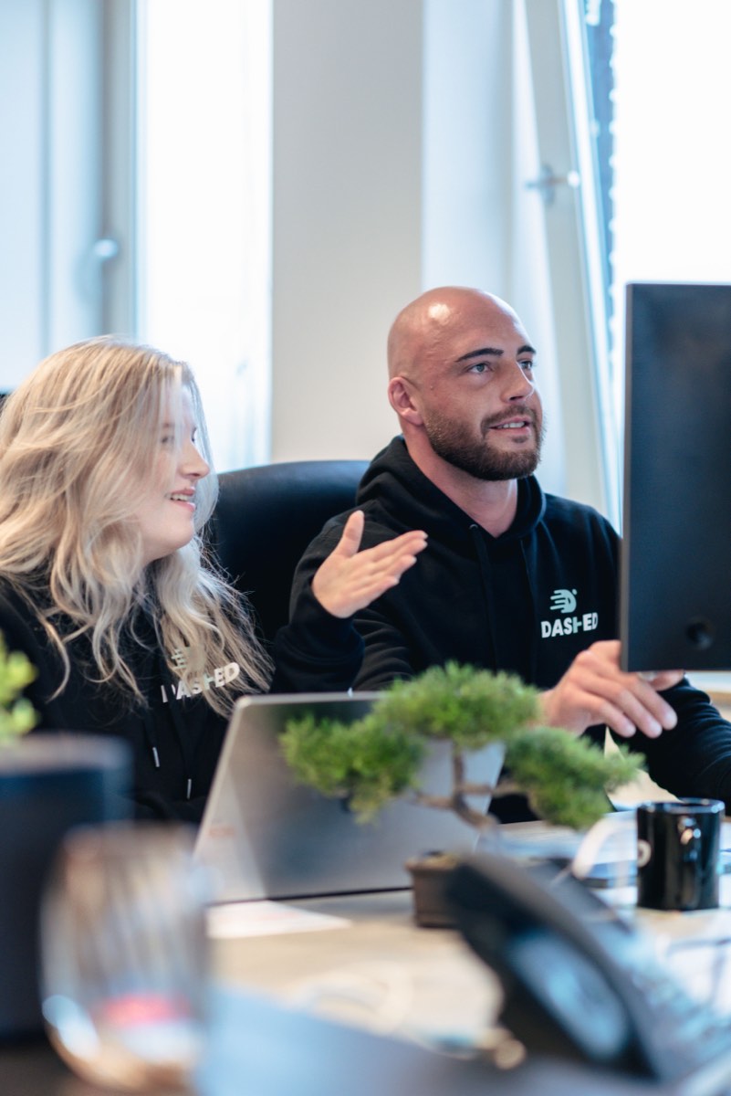 Twee collega's in gesprek achter hun bureau