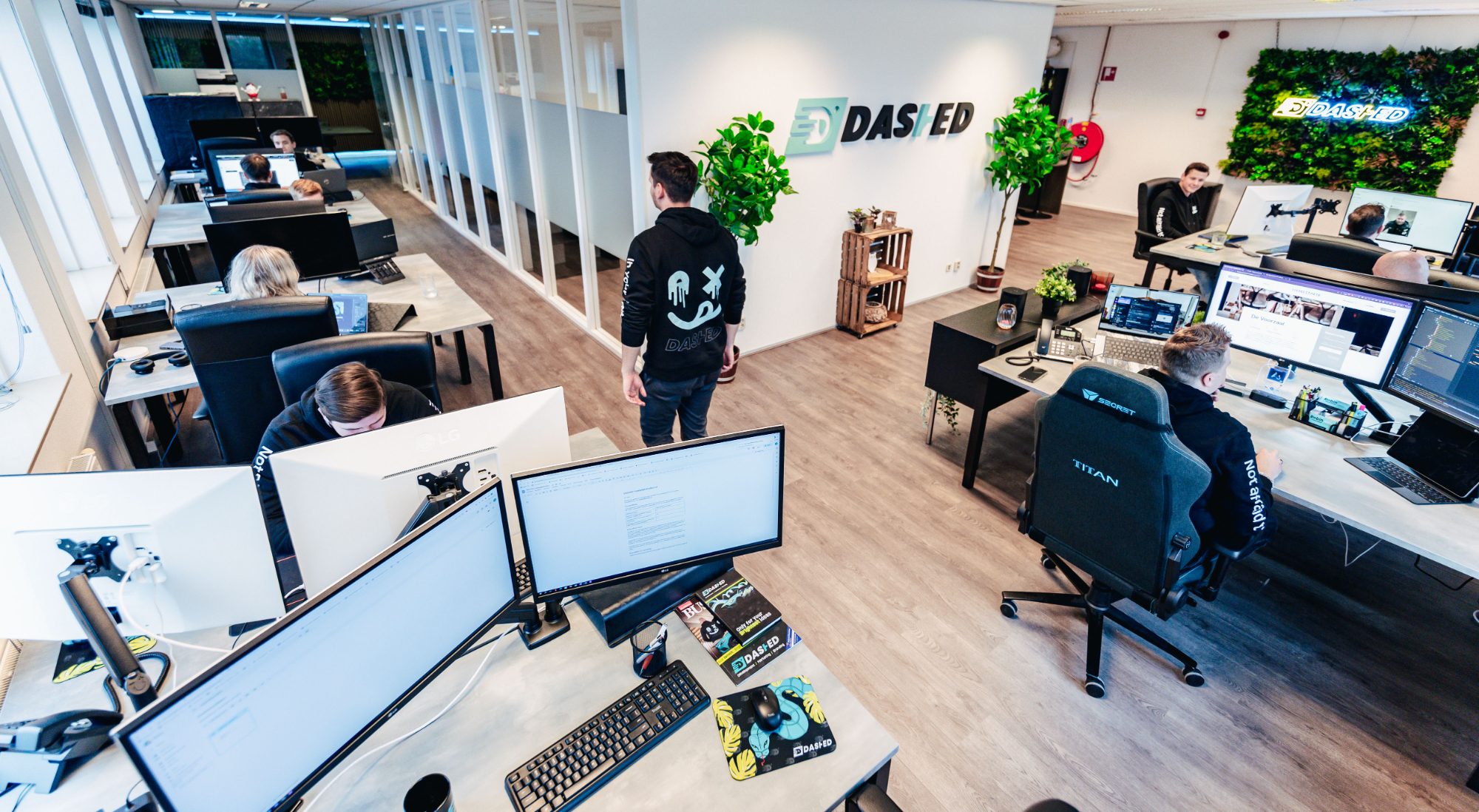 Het kantoor van Dashed in Wijchen: developers aan het werk met de Dashed-logowand op de achtergrond