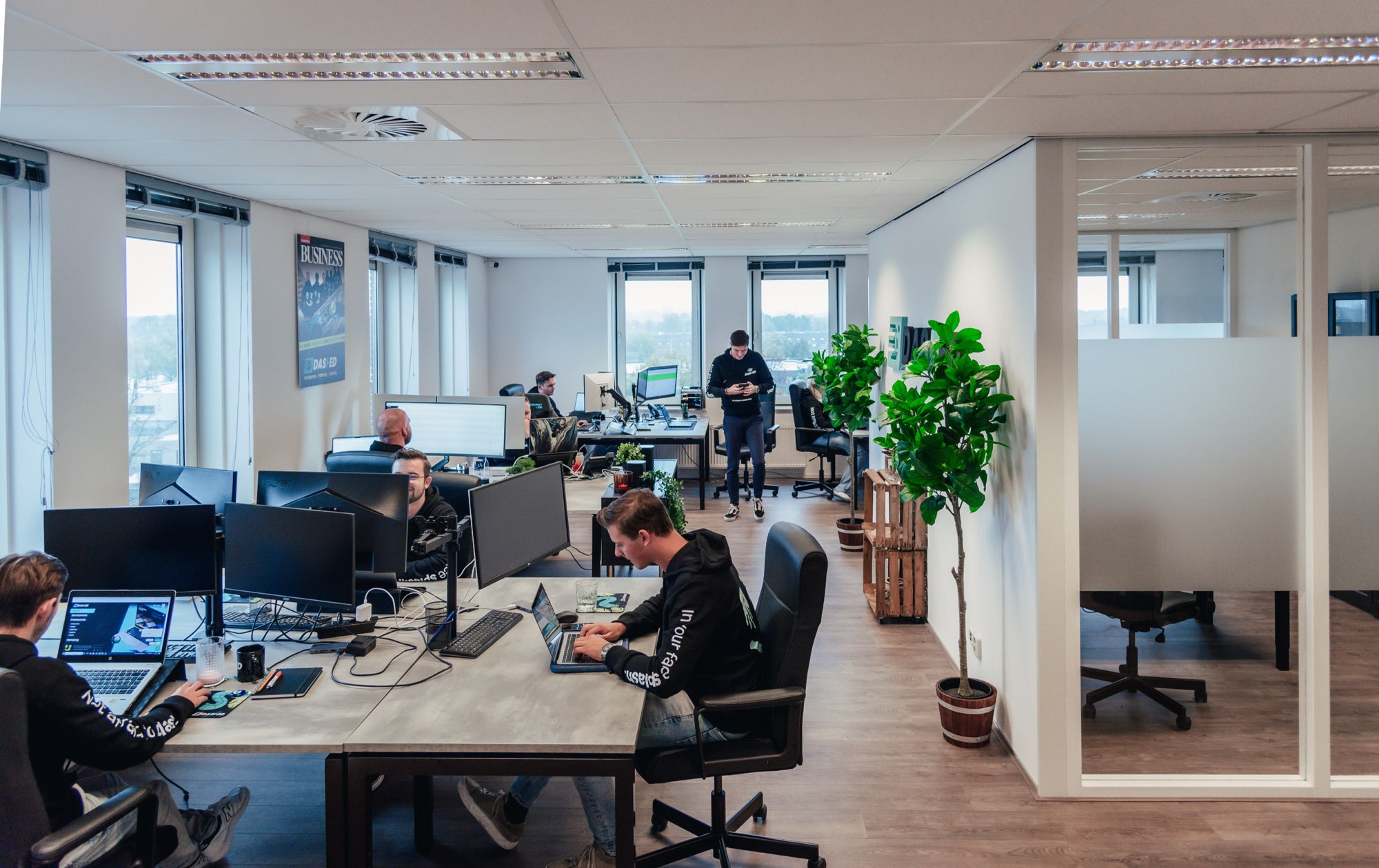 Kantoortuin met werkplekken, dubbele schermen en planten