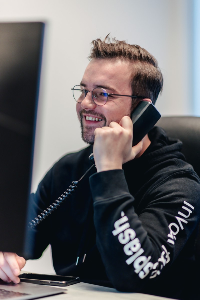 Medewerker in gesprek aan de telefoon achter zijn bureau