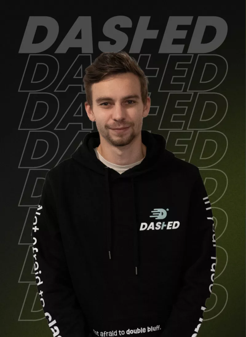 Man in zwarte hoodie met het logo "DASHED" staat voor een achtergrond met herhaalde tekst "DASHED".