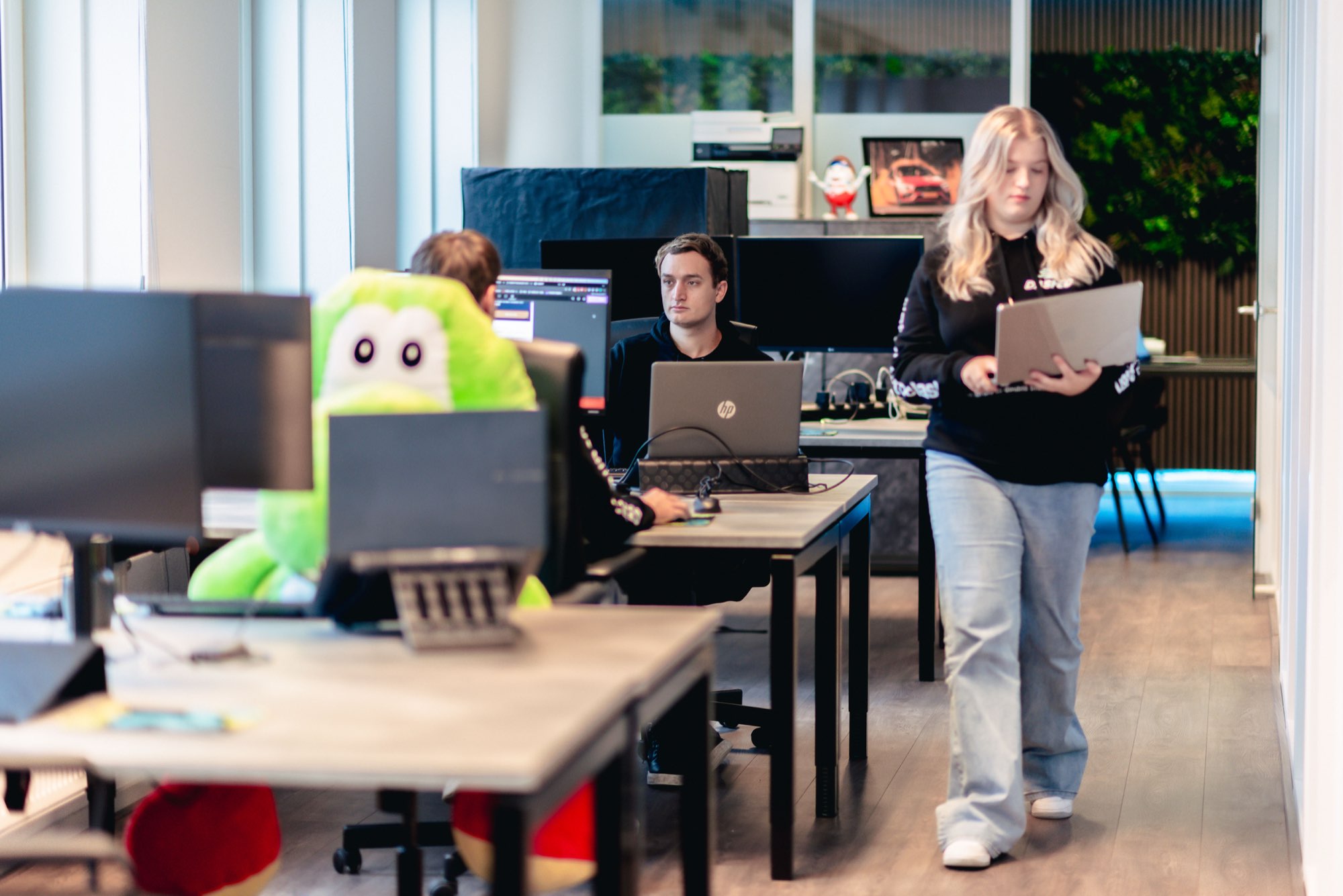 Medewerker loopt met een laptop door de kantoortuin