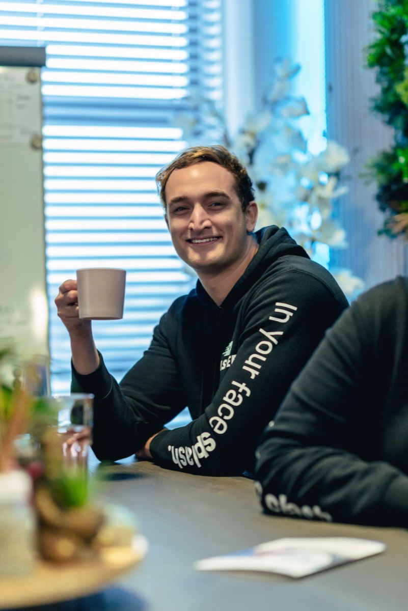 Medewerker met een kop koffie aan de vergadertafel