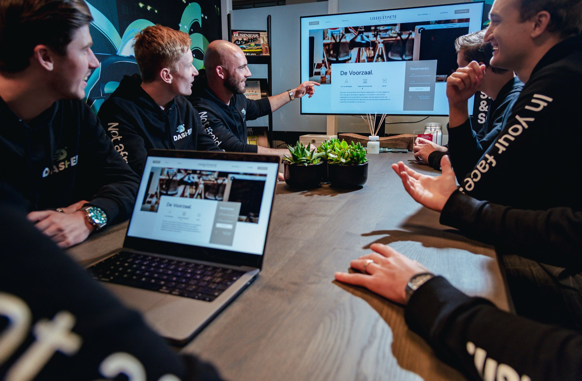 Team bekijkt een presentatie op een laptop tijdens overleg