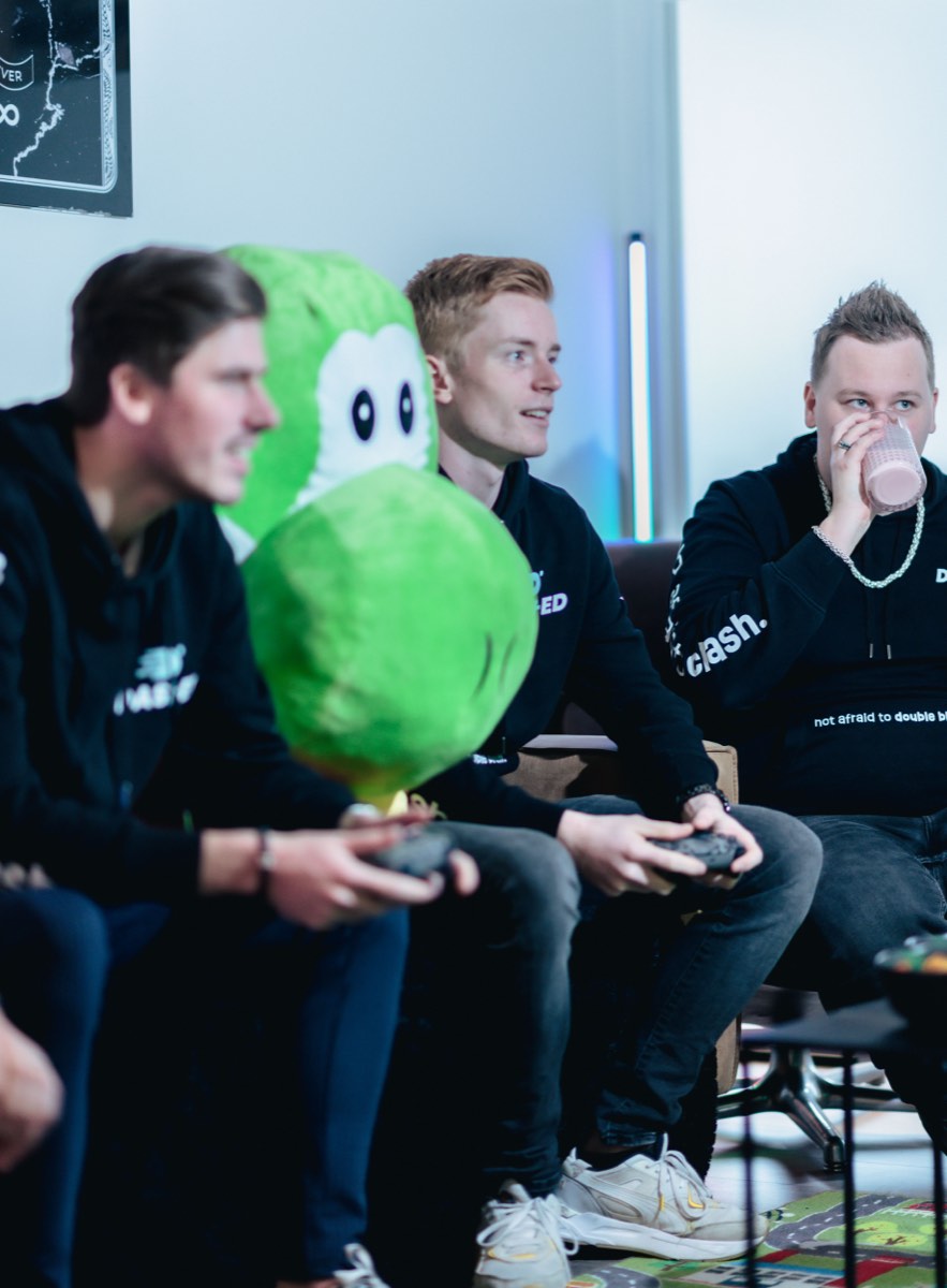 Collega's met gamecontrollers en de groene mascotte
