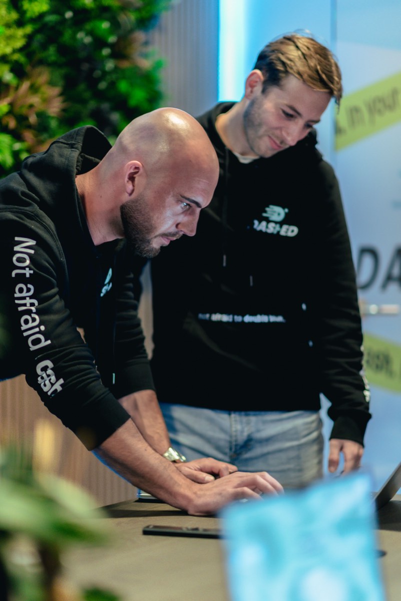 Twee collega's overleggen samen achter een werkplek