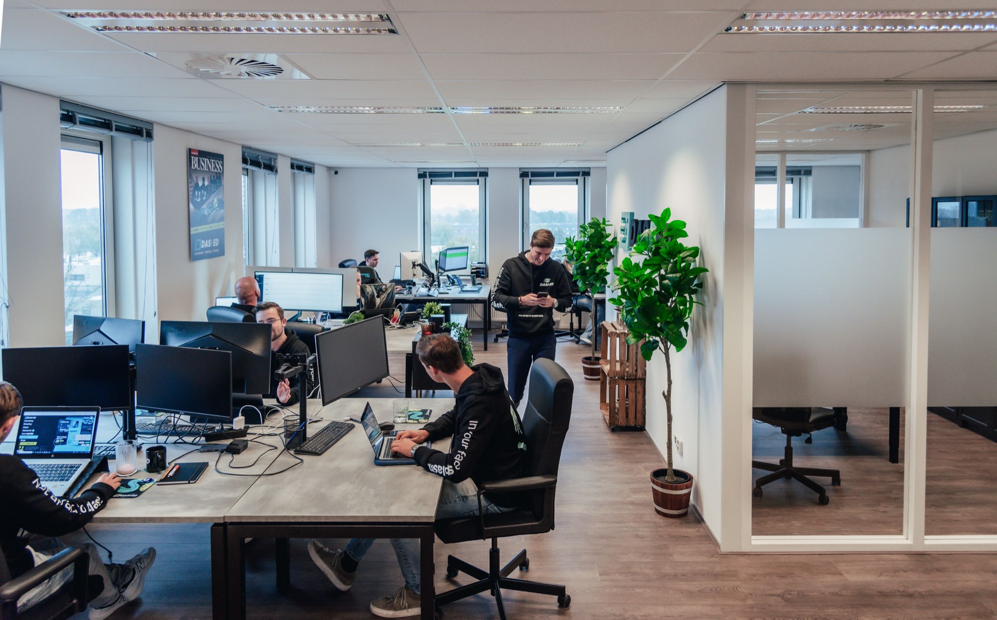 Kantoortuin met werkplekken en een medewerker bij de plantenwand