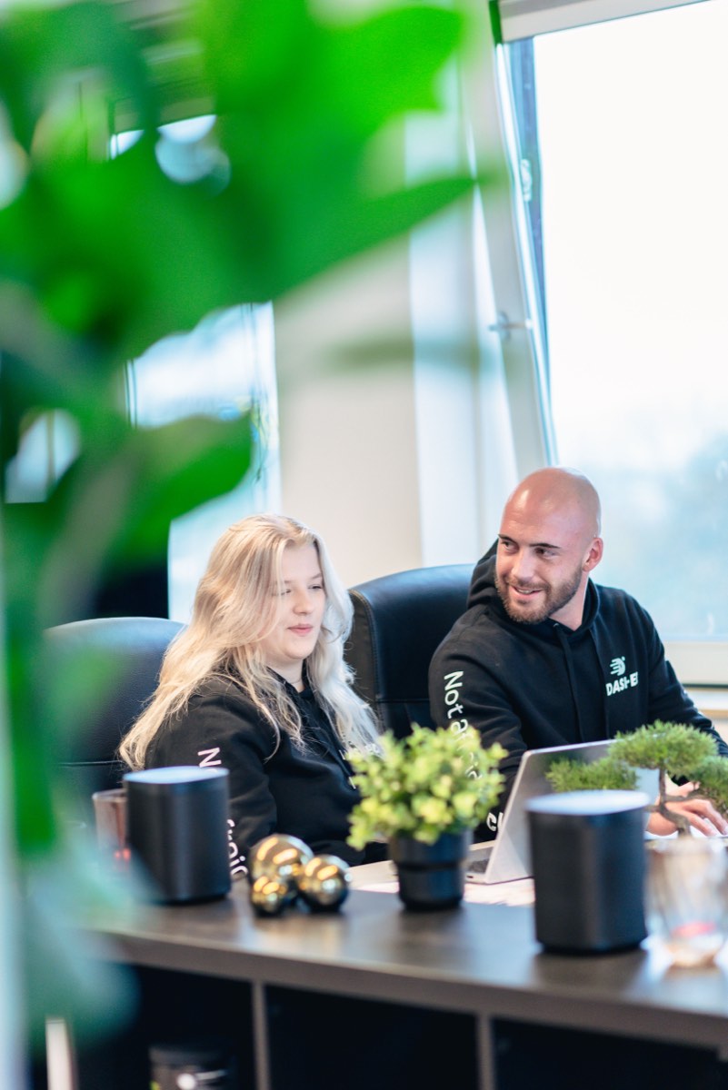 Collega's in gesprek achter hun werkplek met planten op de voorgrond