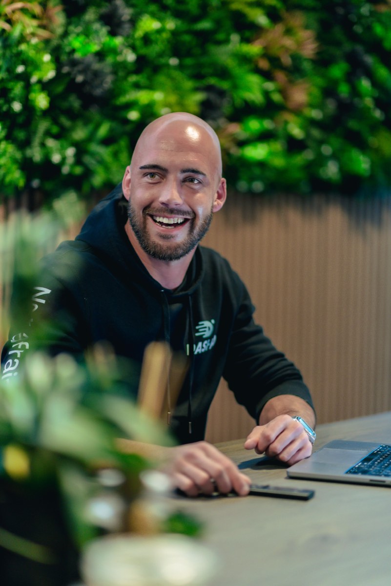 Lachende medewerker aan de vergadertafel voor de plantenwand