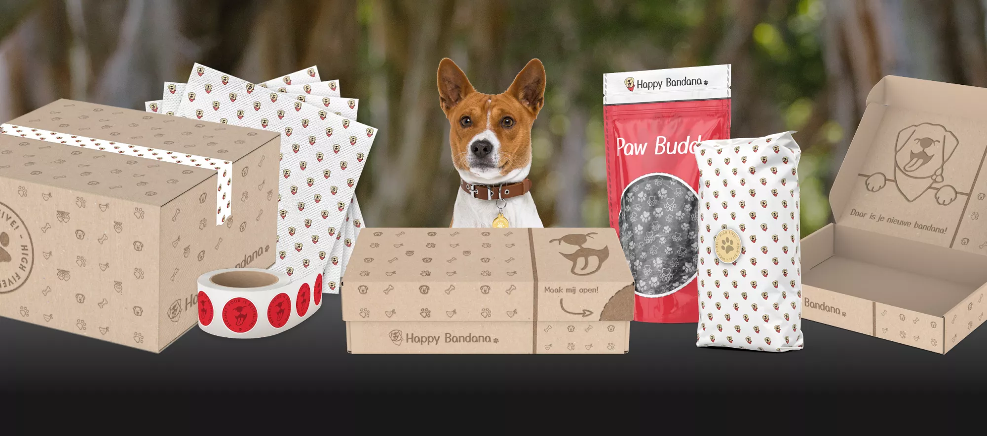 Hond met kartonnen dozen en verpakkingen van Happy Bandana, inclusief tape, servetten en een rode zak met opdruk.