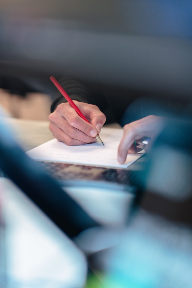Iemand maakt aantekeningen met een rode pen in een notitieboek