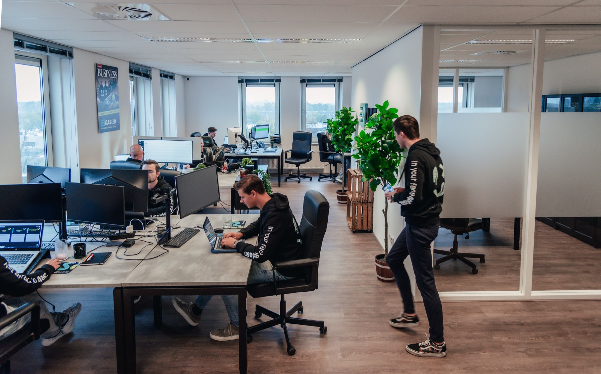 Medewerker aan het werk in de kantoortuin met bureaus en planten