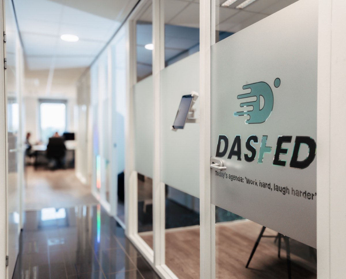 Kantoorgang met glazen wand en het Dashed-logo
