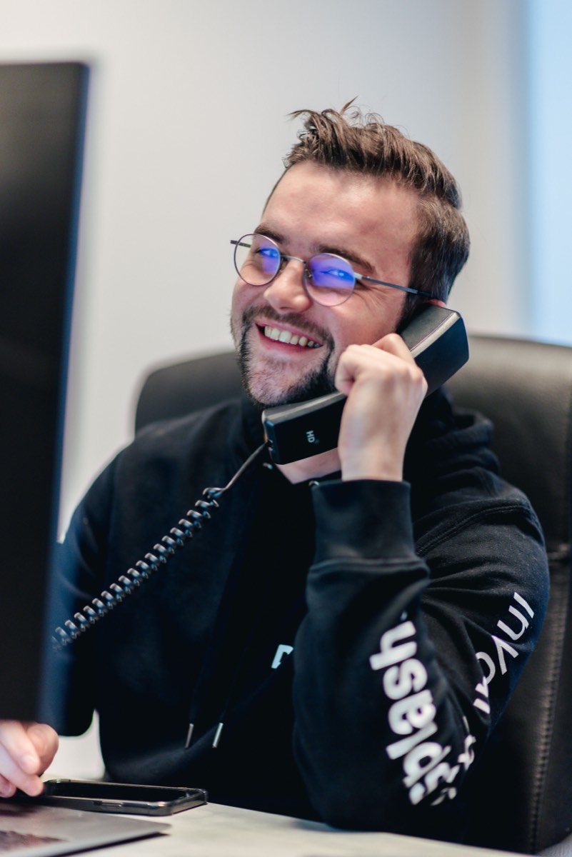 Lachende medewerker aan de telefoon op zijn werkplek