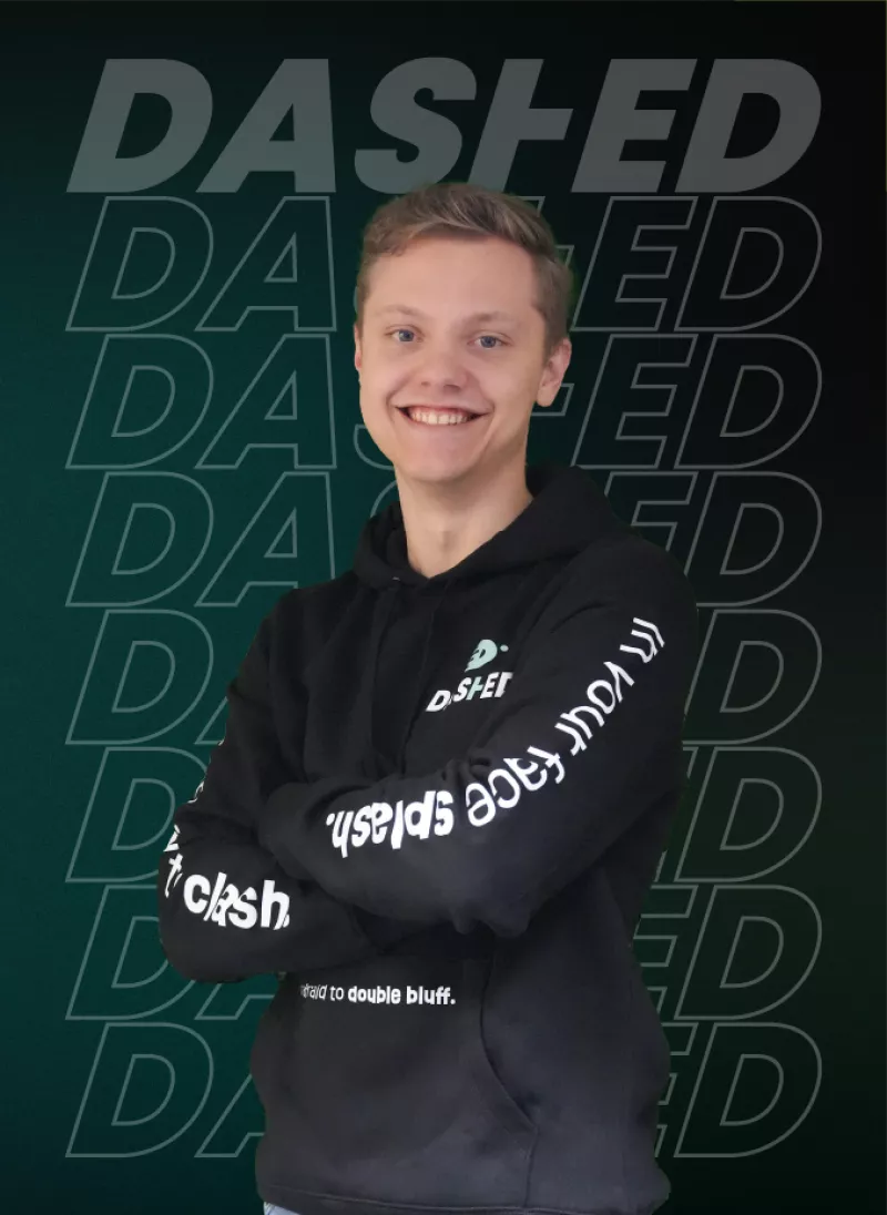 Een persoon in een zwarte hoodie met gekruiste armen voor een achtergrond met de tekst "DASHED" in verschillende tinten groen.