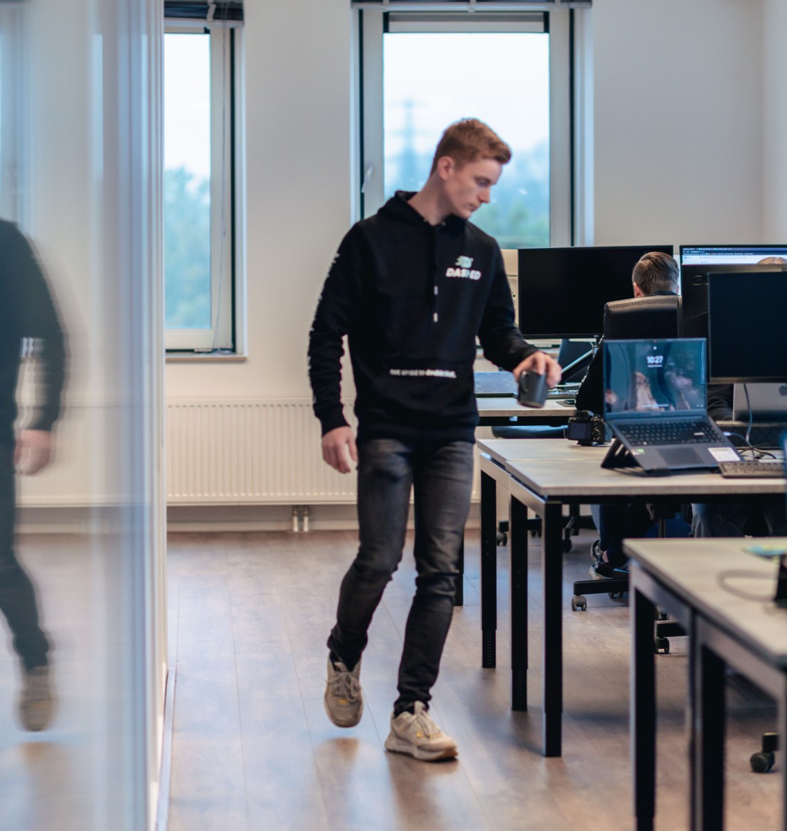 Medewerker loopt langs de werkplekken in de kantoortuin