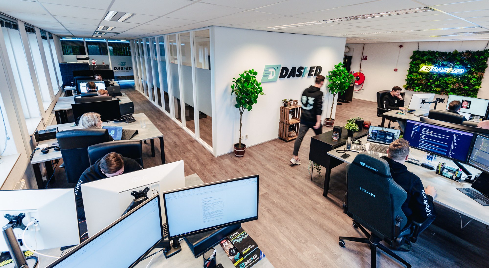 Kantoortuin met bureaus, planten en een medewerker aan het werk