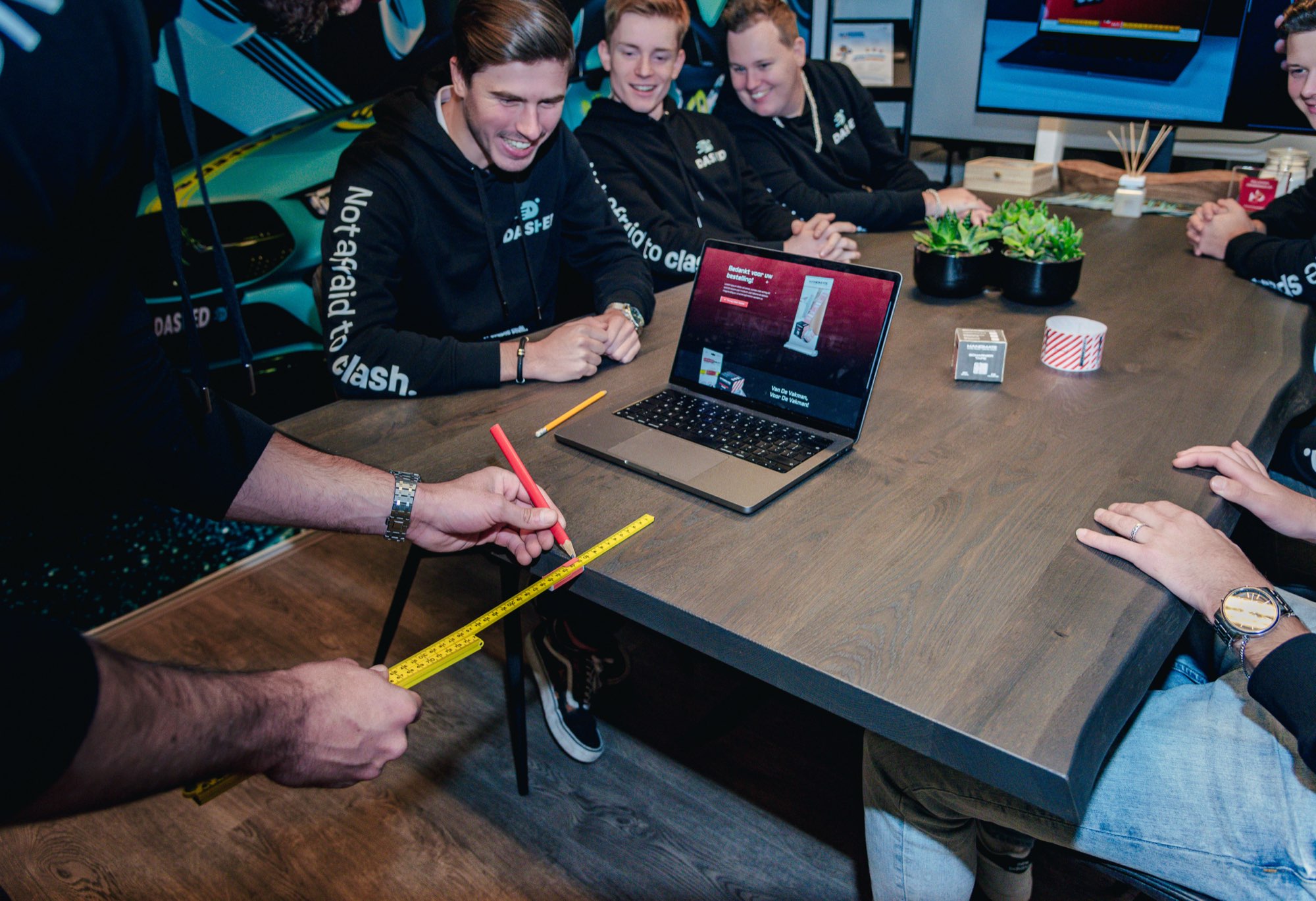 Teamoverleg aan de houten vergadertafel met laptops en aantekeningen