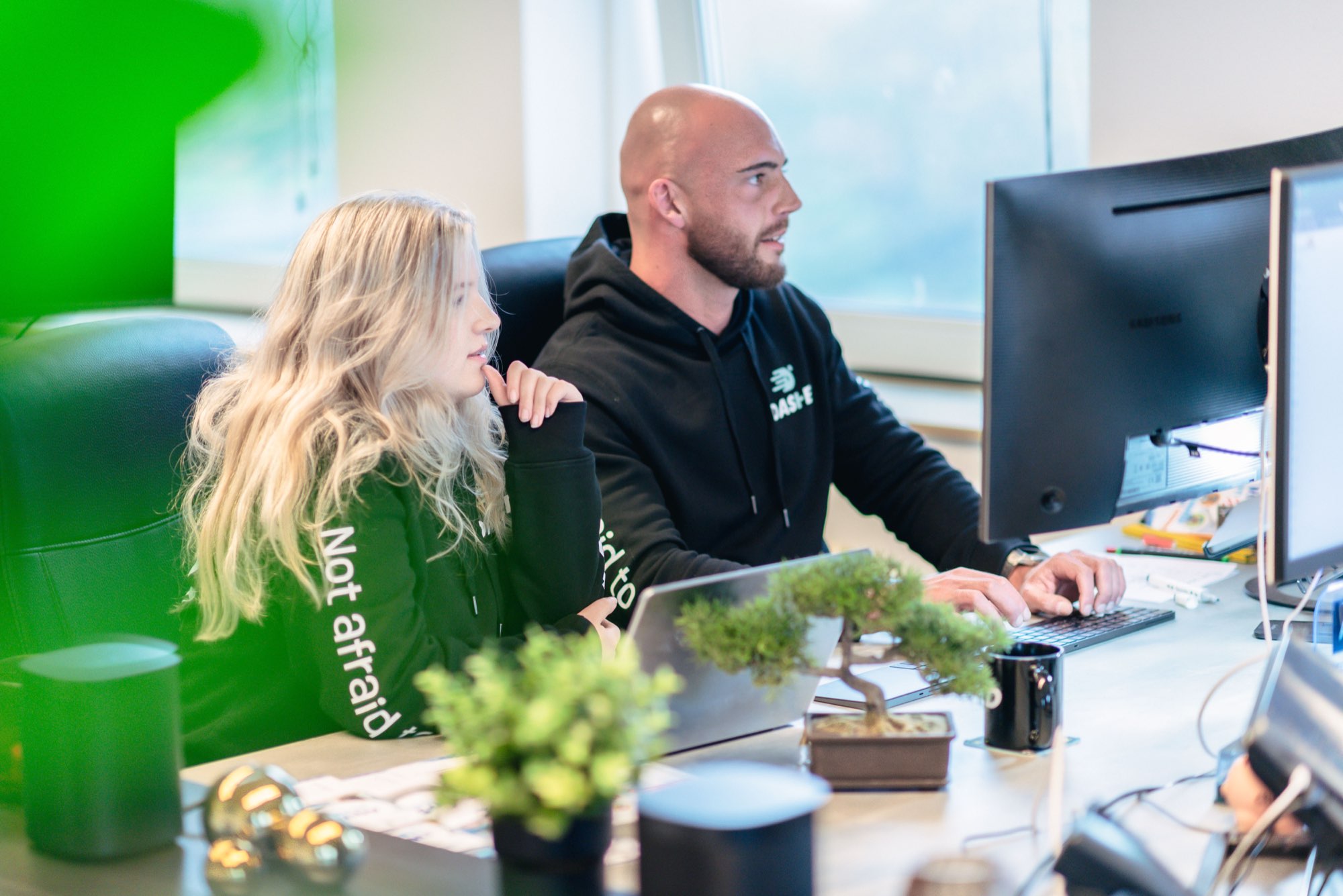 Twee collega's overleggen achter een scherm voor de groene wand