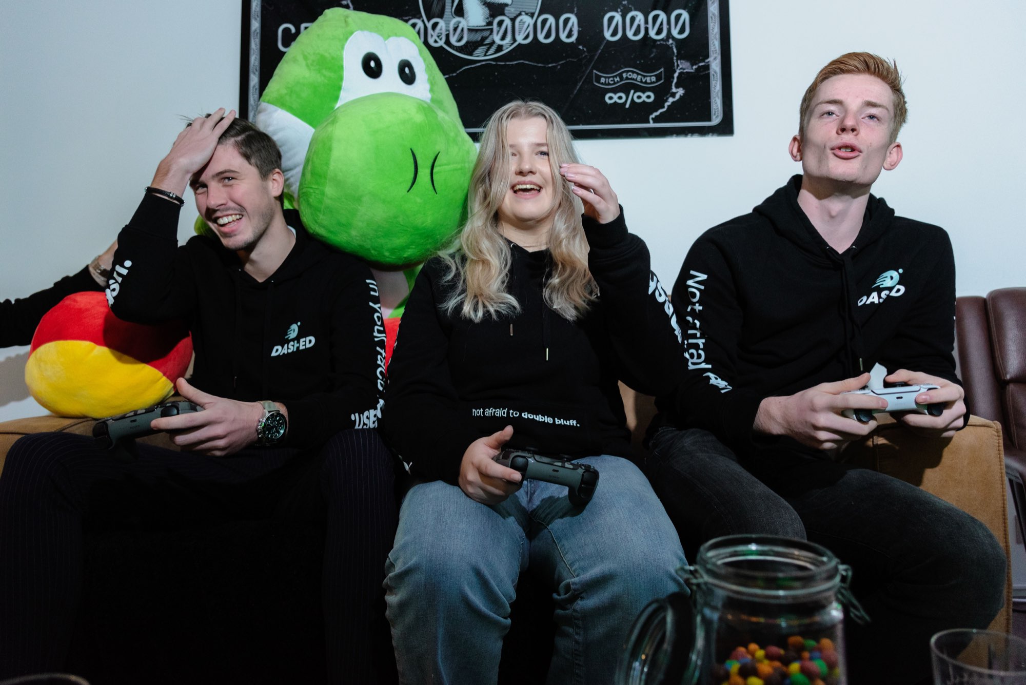 Drie collega's gamen op de bank met de groene mascotte
